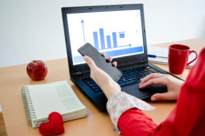 women holding cell phone at desk