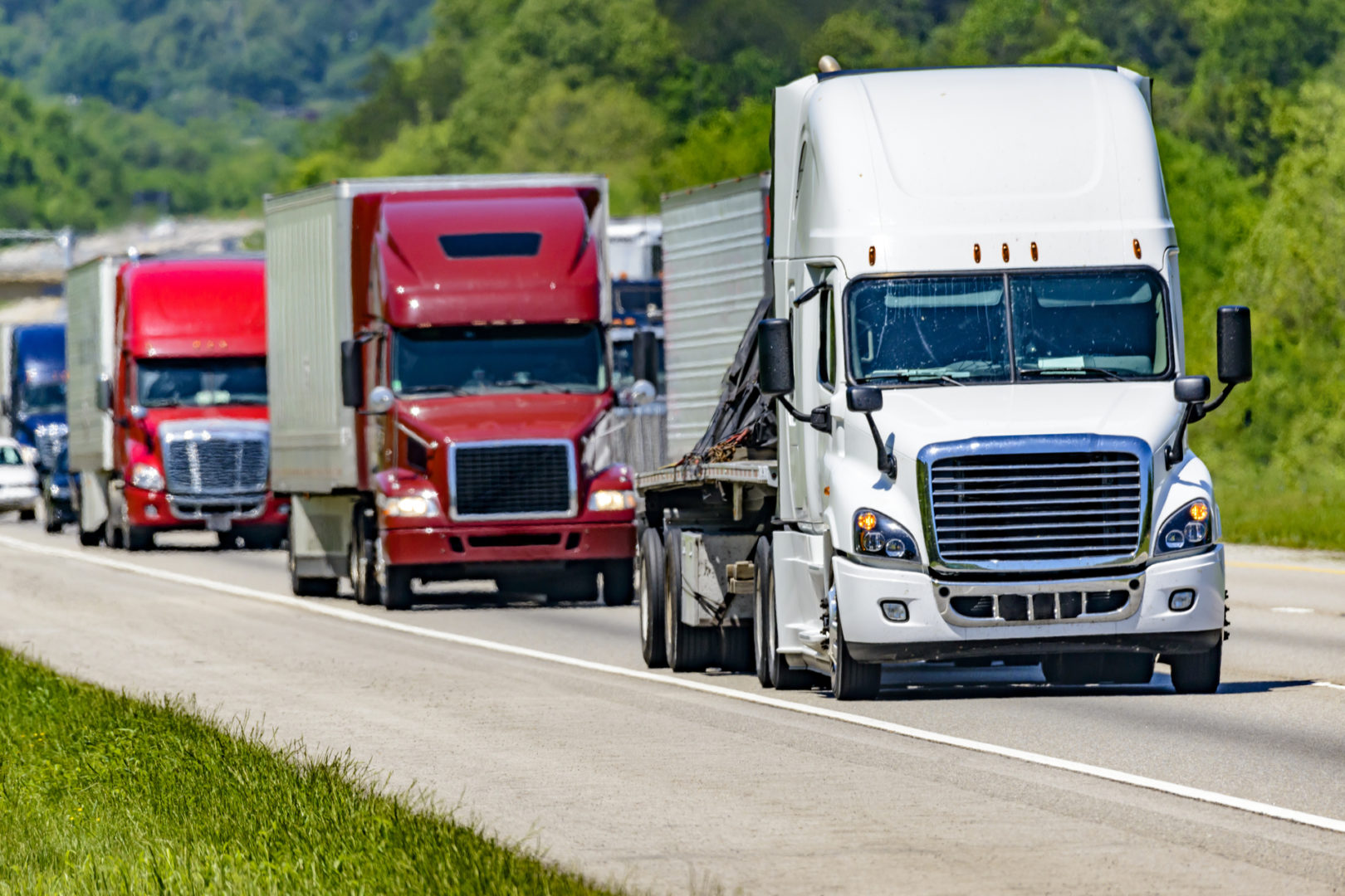 A solid line of eighteen-wheelers barrel down an interstate highway in Tennessee.